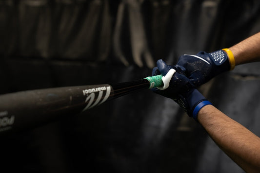 Hands holding a bat and swinging with a Launchpad thumb guard on