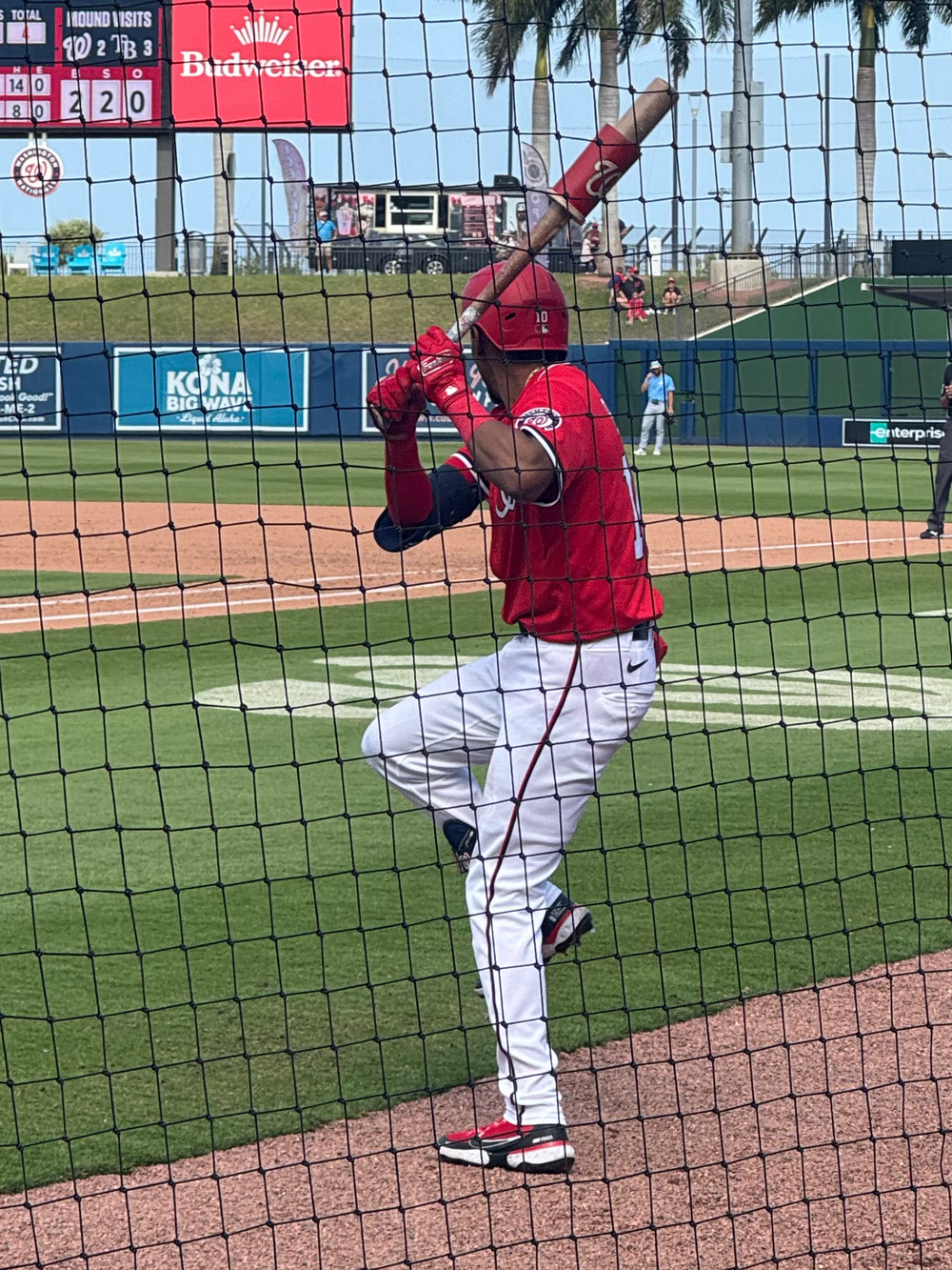 Washington Nats player in Red swings a bat in on-deck circle