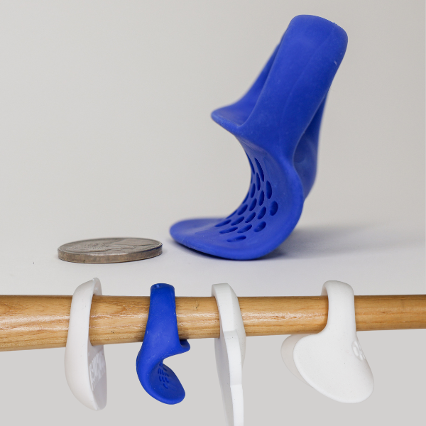 Launchpad next to a nickel, showing how it is thinner than other thumb guards without sacrificing shock absorption