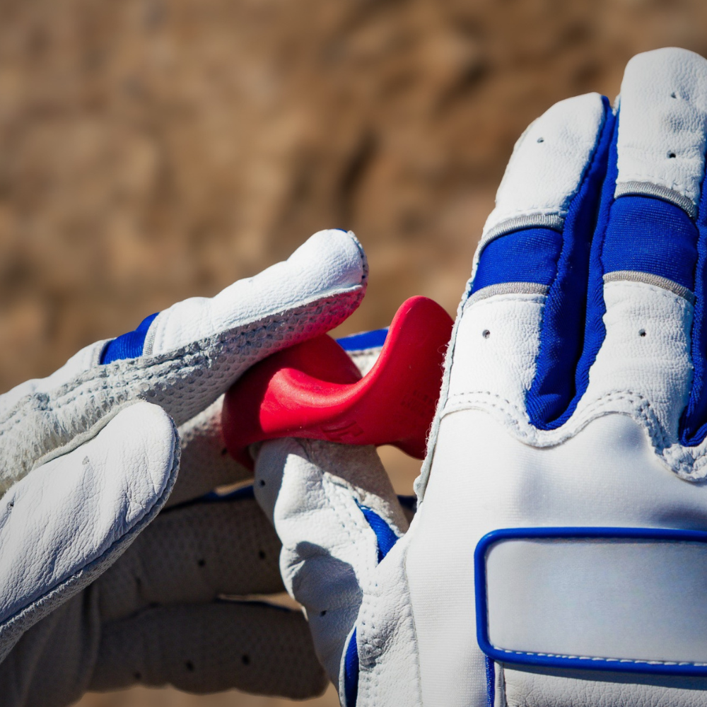 Close up of hands with baseball gloves on putting on a red baseball thumb guard